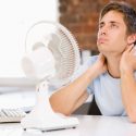 man-with-broken-ac-unit-using-fan